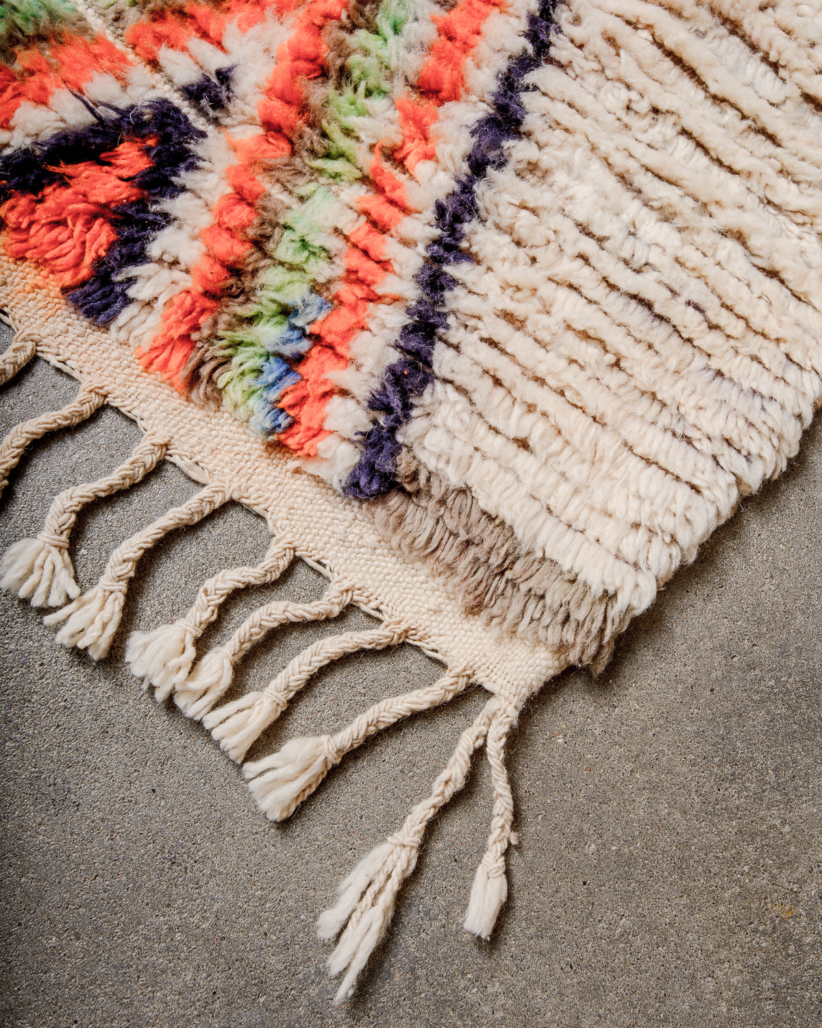Corner of Berber runner rug with fluffy wool pile and natural wool tassels.